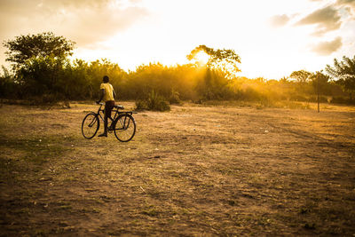 Boy riding bicycle on field against sky