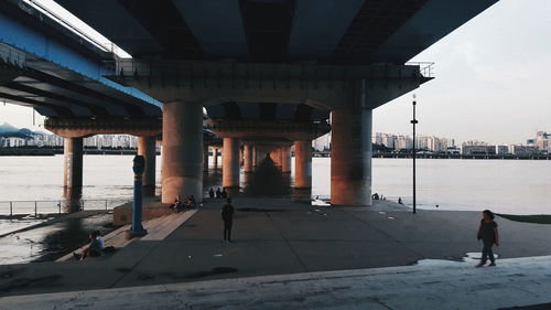 Rear view of woman walking under bridge in city during winter