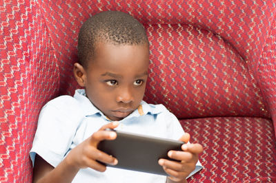 Child holds the mobile phone but looks up the work of the hairdresser