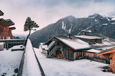 Snow covered houses by buildings against sky