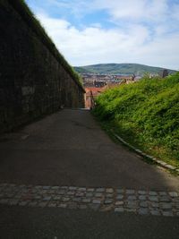 Road by buildings against sky