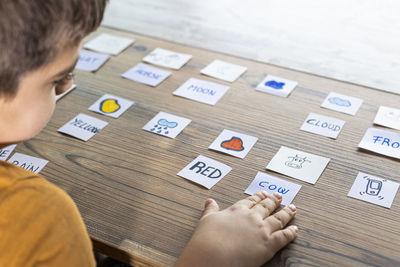 High angle view of boy holding text on table