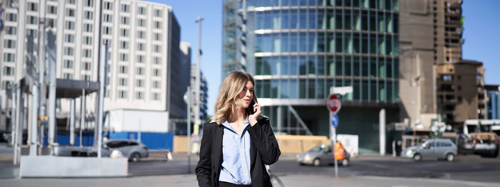 Rear view of woman standing against buildings in city