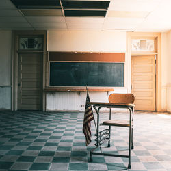 American flag on table by empty chair over tiled floor