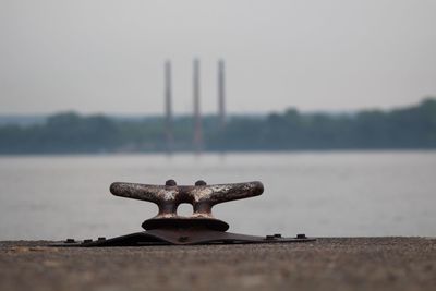 Close-up of rusty chain on lake against sky