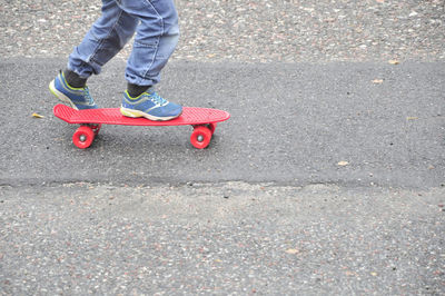 Low section of boy skateboarding on road