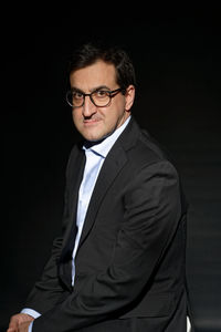 Portrait of young man wearing sunglasses against black background