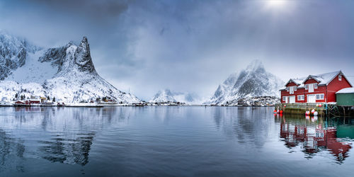 Scenic view of lake by snowcapped mountains against sky