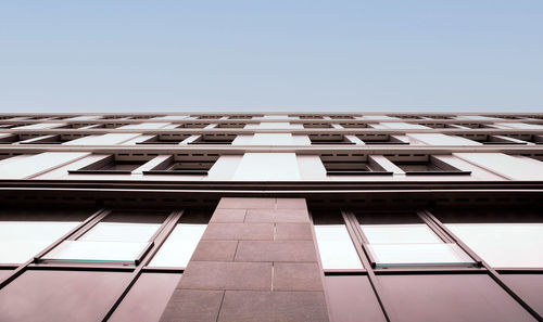 Upward view of a building showcasing geometric window patterns and the contrast of its facade