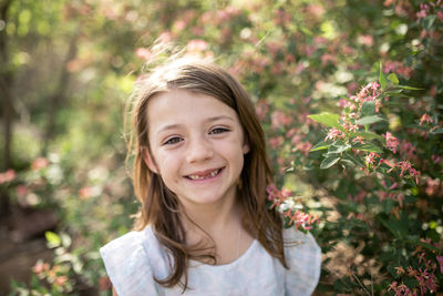 Close-up portrait of happy girl standing by plants at park