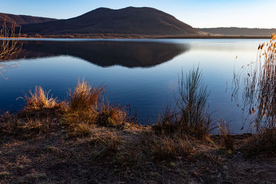 Scenic view of lake by mountains against sky