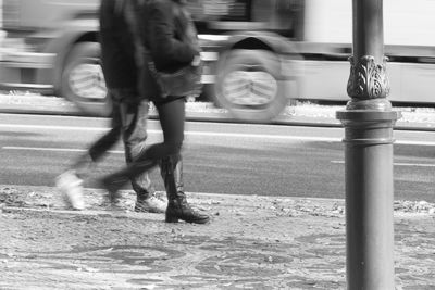 Low section of man with umbrella on street in city