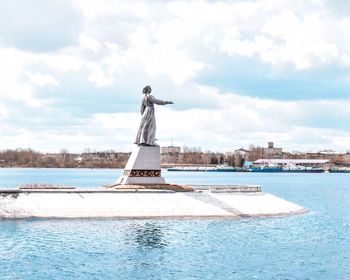 Statue by sea against sky