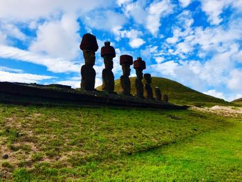 Statues in row on landscape against sky