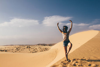 Woman standing on sand at beach against sky