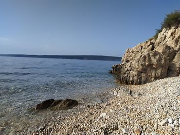 Rock formation on beach against sky