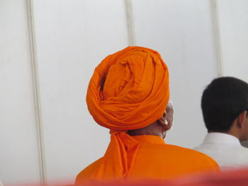 Rear view of people standing against orange wall