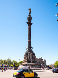 Statue in city against clear blue sky