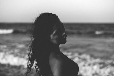 Side view of young woman standing at beach