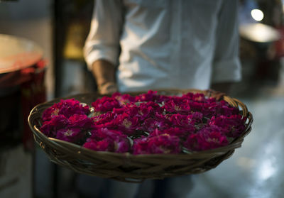 Midsection of man holding basket full of roses