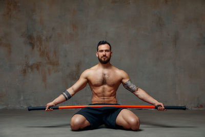 Man with stick sitting against wall