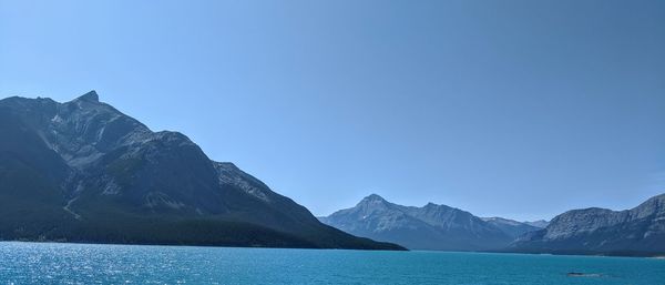 Scenic view of sea and mountains against clear blue sky