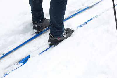 Low section of person standing on snow covered land