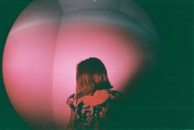 Rear view of man standing against pink wall