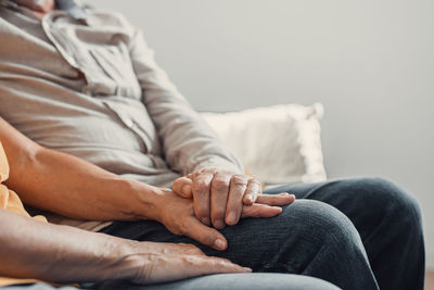 Midsection of man sitting on sofa at home