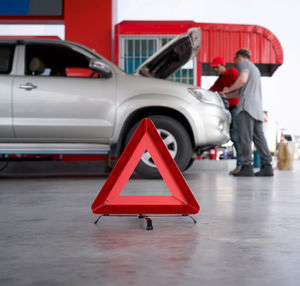 Side view of man standing on red car