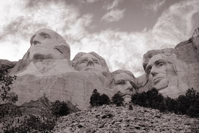 Low angle view of statues against cloudy sky