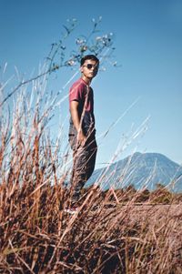 Man seen through plants standing on field against sky