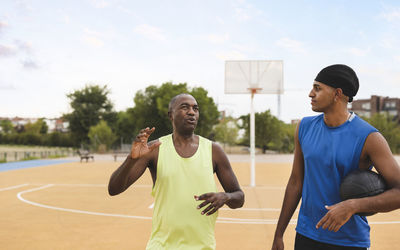 Mature man talking with son at basketball court