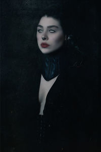 Portrait of beautiful young woman against black background