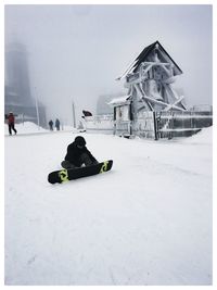 People on snow covered building against sky