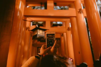 Close-up of woman photographing torii gate through mobile phone