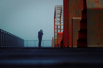 Man photographing on pier against sky