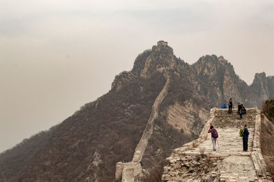 People on rock formation against sky