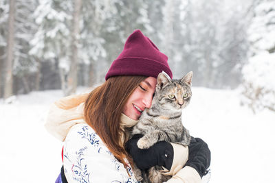 Woman embracing cat during winter