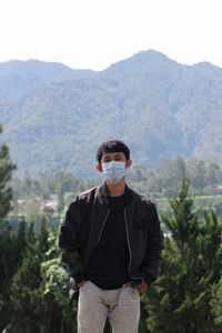 Young man standing on mountain against sky