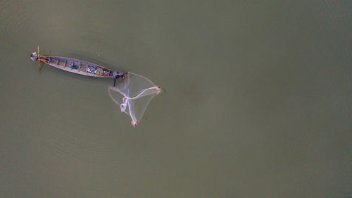 High angle view of fisherman throwing net at river