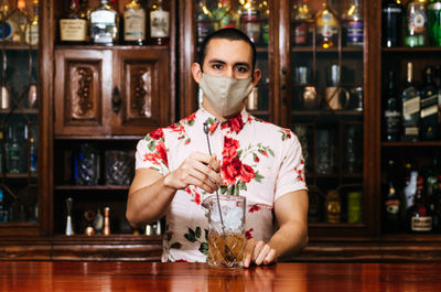 Portrait of man holding drink on bar counter