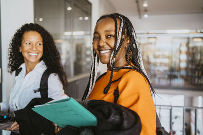 Portrait of smiling braided female student with friend in university