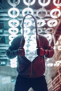 Close-up of hand hanging on illuminated lighting equipment