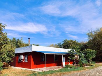 House and trees on field against sky