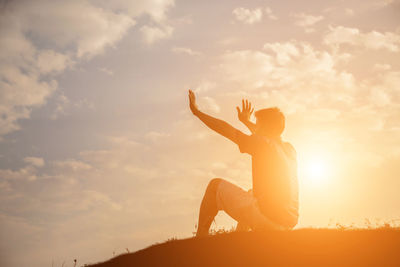 Low angle view of man sitting against sky during sunset