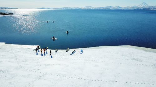 High angle view of people paddleboarding in sea during winter