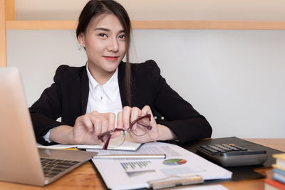 Portrait of businesswoman holding eyeglasses at office