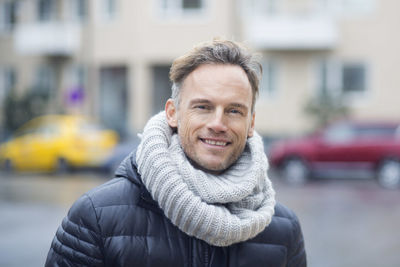 Portrait of smiling mature man on street against building