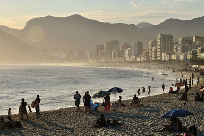 People at beach against sky during sunset